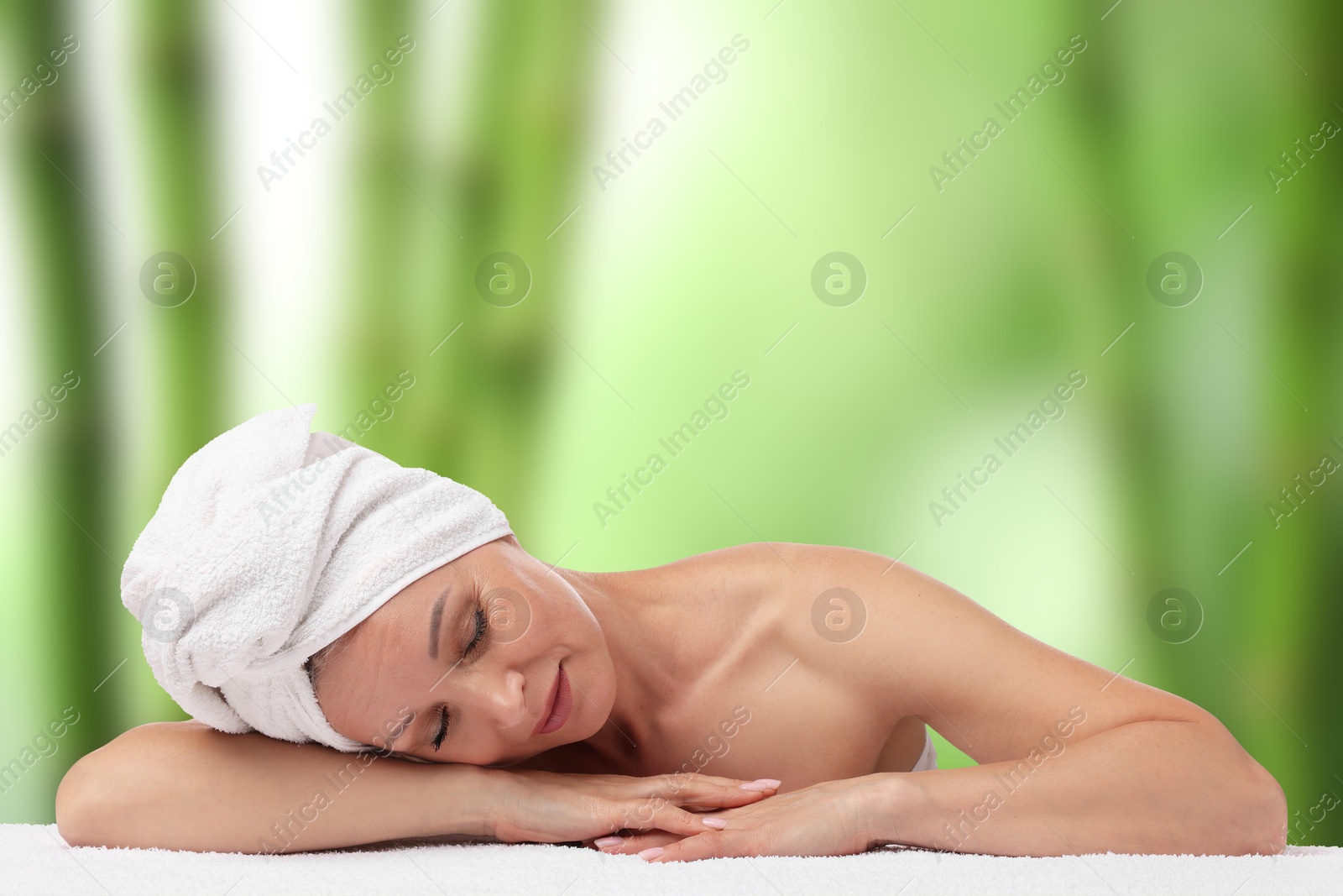 Beautiful woman relaxing on towel against blurred green background. Spa center Image of Beautiful woman relaxing on towel against blurred green background. Spa center