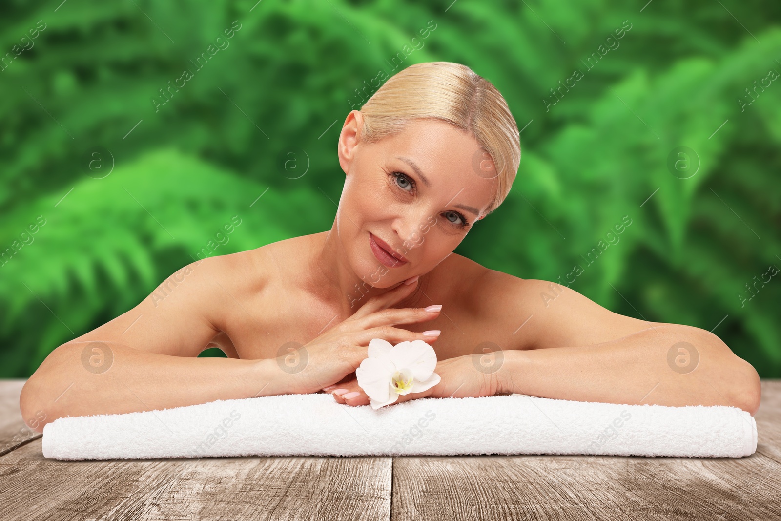 Beautiful woman relaxing on wooden surface against blurred green background. Spa center Image of Beautiful woman relaxing on wooden surface against blurred green background. Spa center