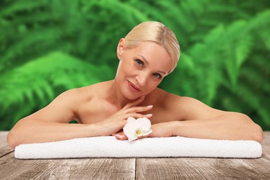 Image of Beautiful woman relaxing on wooden surface against blurred green background. Spa center