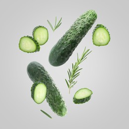 Image of Fresh cucumbers and rosemary falling against grey background