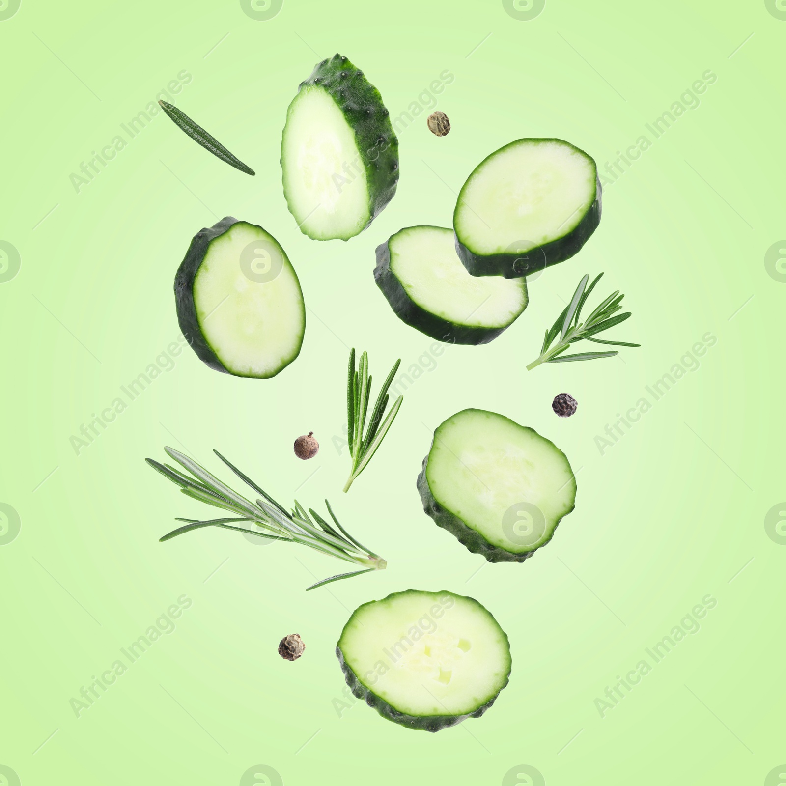 Image of Cucumber slices and rosemary flying against green background