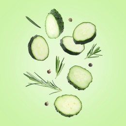 Image of Cucumber slices and rosemary flying against green background