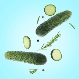 Image of Fresh cucumbers and rosemary falling against light blue background