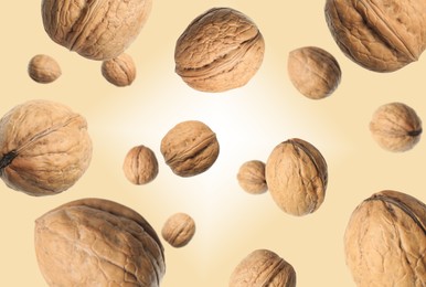 Image of Walnuts in shell swirling in air against dark beige background
