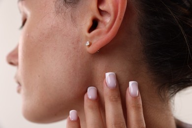 Photo of Woman wearing stylish earring on light background, closeup