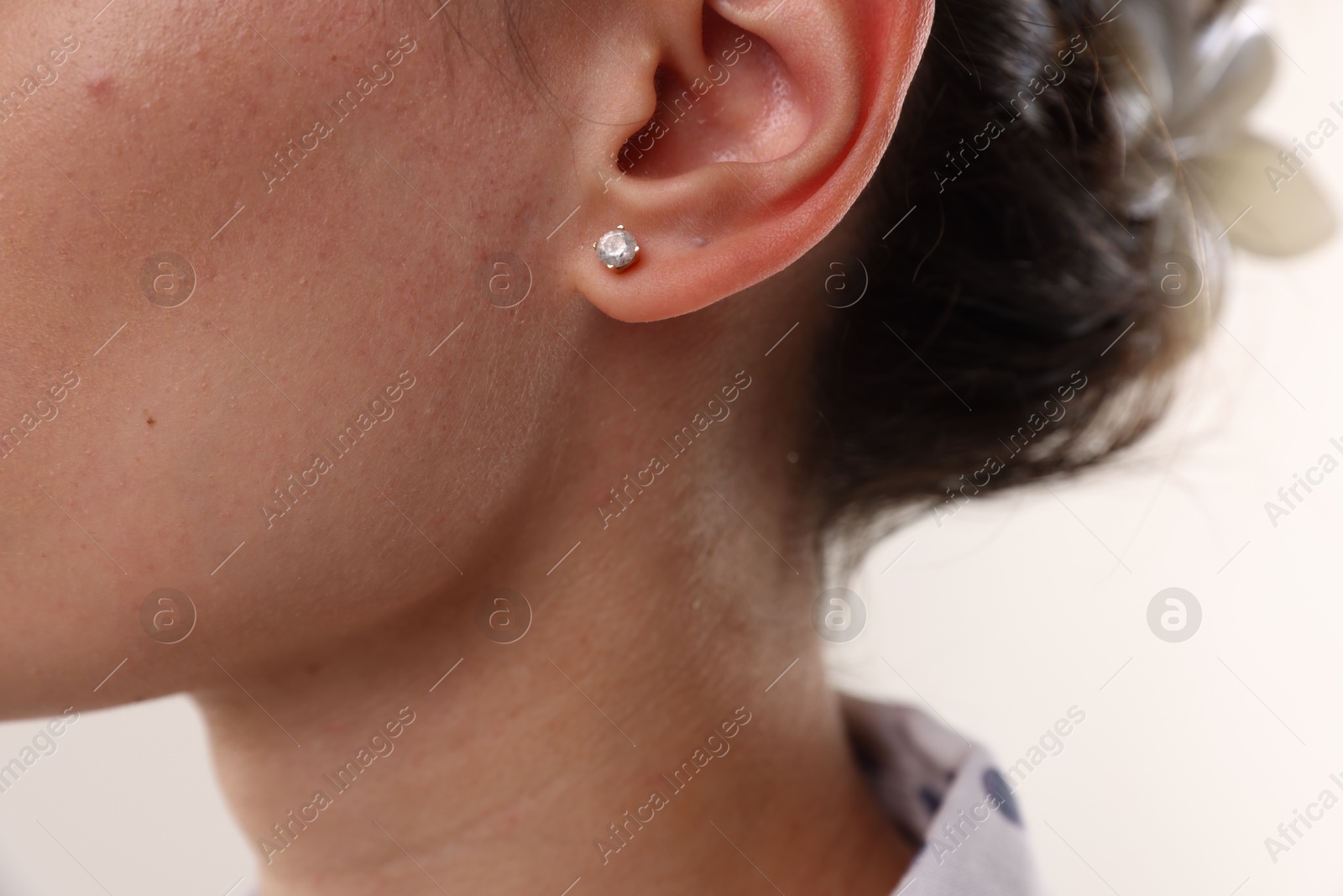 Photo of Woman wearing stylish earring on light background, closeup