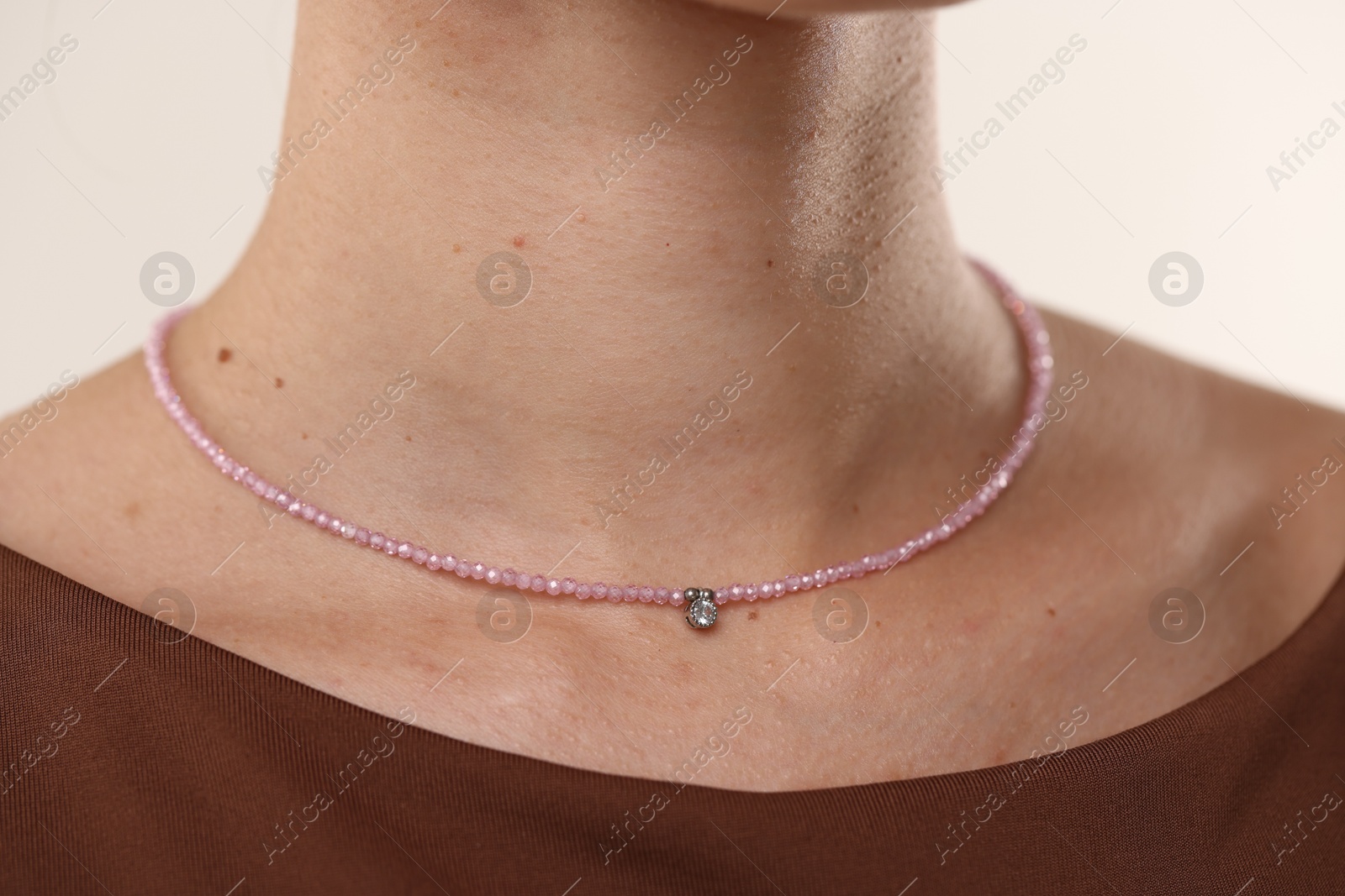 Photo of Woman wearing stylish necklace on light background, closeup