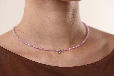 Photo of Woman wearing stylish necklace on light background, closeup