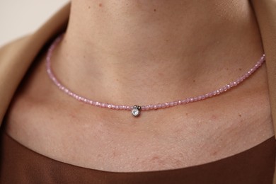 Photo of Woman wearing stylish necklace on light background, closeup