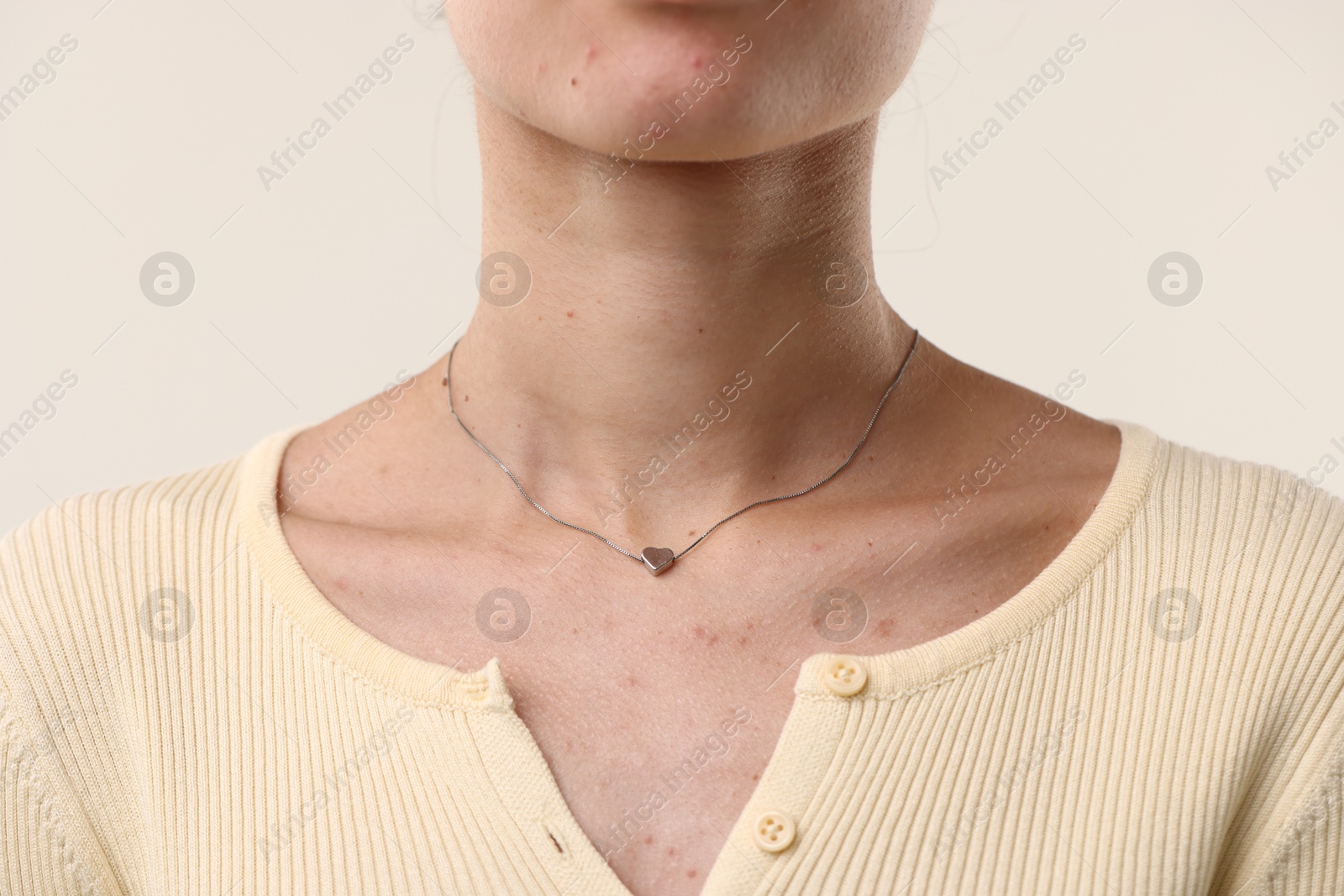 Photo of Woman wearing silver necklace on light background, closeup