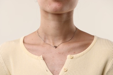 Photo of Woman wearing silver necklace on light background, closeup