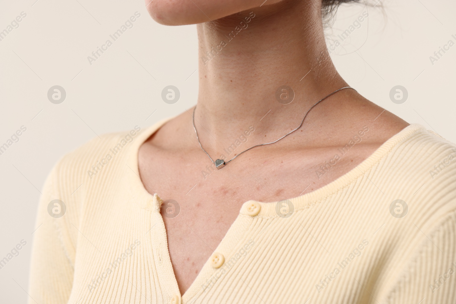 Photo of Woman wearing silver necklace on light background, closeup