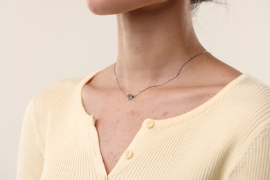Photo of Woman wearing silver necklace on light background, closeup