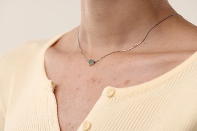Photo of Woman wearing silver necklace on light background, closeup