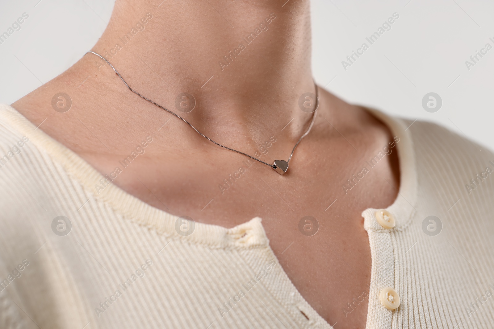 Photo of Woman wearing silver necklace on light background, closeup
