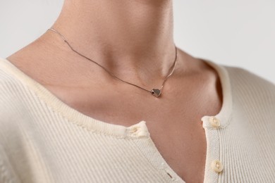 Photo of Woman wearing silver necklace on light background, closeup