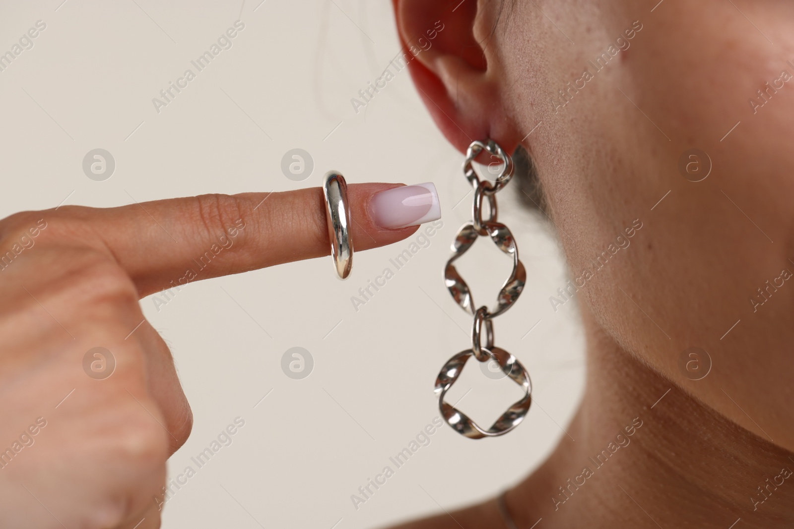 Photo of Woman wearing stylish earring and ring on light background, closeup
