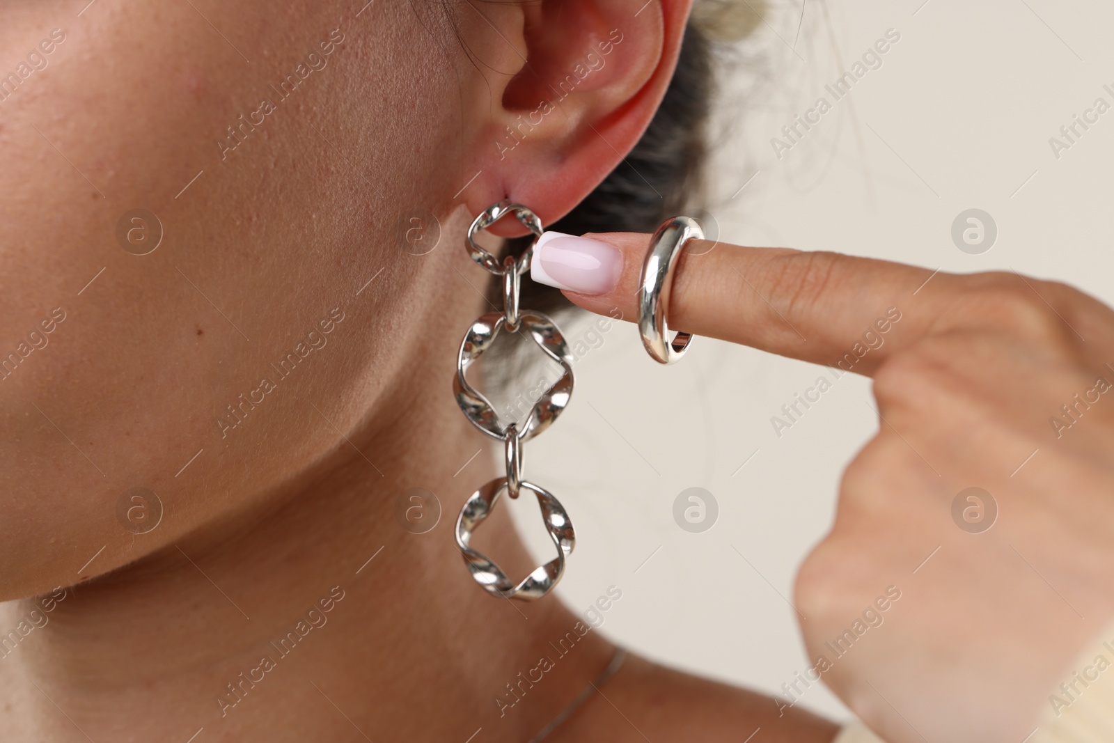 Photo of Woman wearing stylish earring and ring on light background, closeup