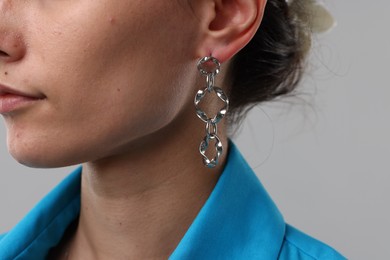 Photo of Woman wearing stylish earring on light grey background, closeup