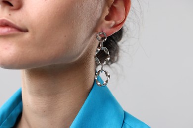 Photo of Woman wearing stylish earring on light grey background, closeup