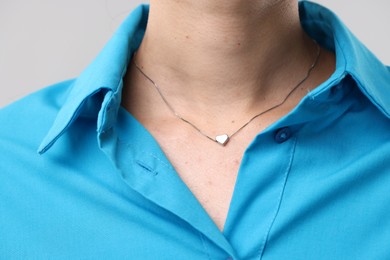 Photo of Woman wearing silver necklace on light grey background, closeup
