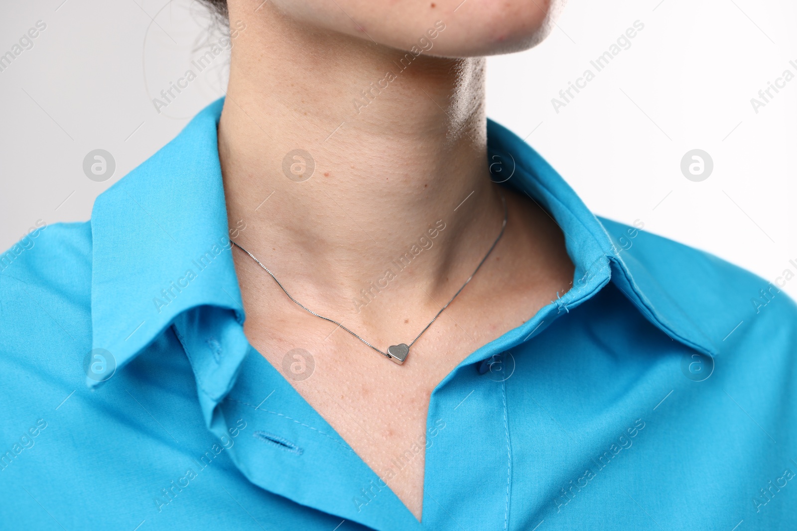 Photo of Woman wearing silver necklace on light grey background, closeup