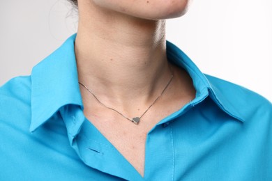 Photo of Woman wearing silver necklace on light grey background, closeup