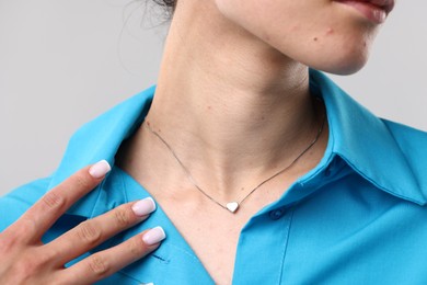 Photo of Woman wearing silver necklace on light grey background, closeup