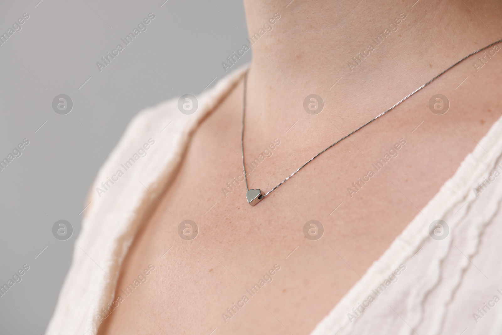Photo of Woman wearing stylish necklace on light grey background, closeup