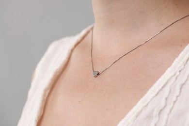 Photo of Woman wearing stylish necklace on light grey background, closeup