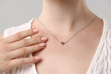 Photo of Woman wearing stylish necklace on light grey background, closeup