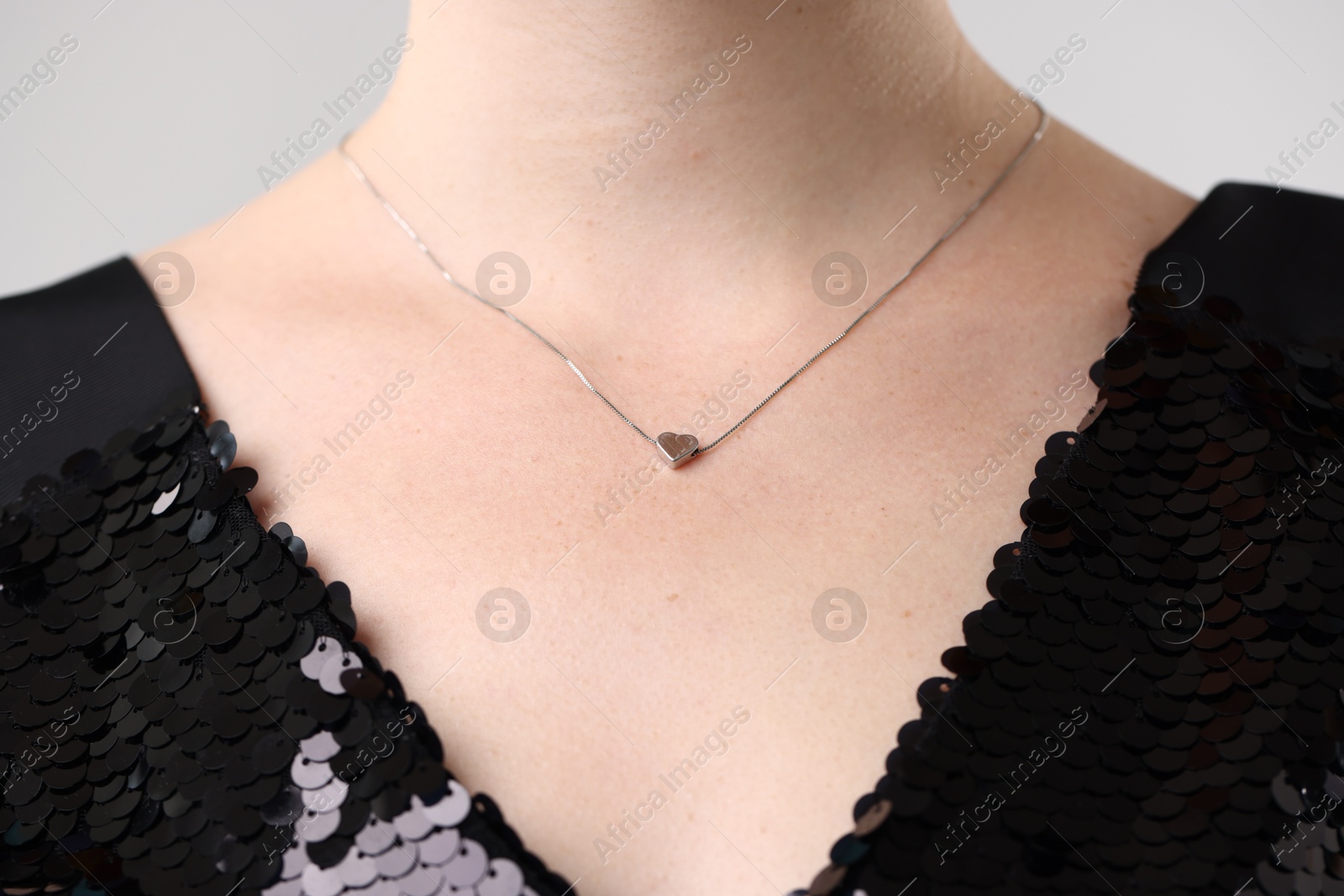 Photo of Woman wearing stylish necklace on light grey background, closeup