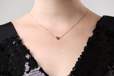 Photo of Woman wearing stylish necklace on light grey background, closeup