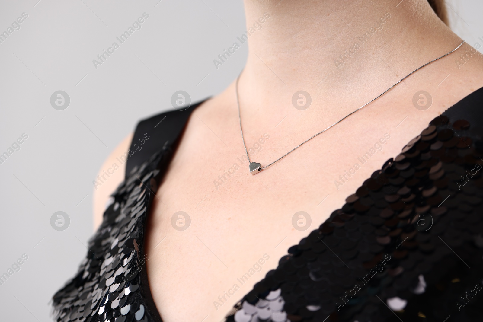 Photo of Woman wearing stylish necklace on light grey background, closeup