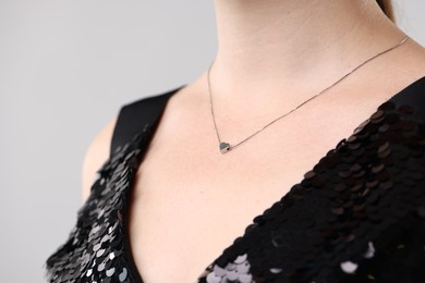 Photo of Woman wearing stylish necklace on light grey background, closeup