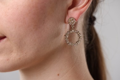 Photo of Woman wearing stylish earring on grey background, closeup
