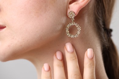 Photo of Woman wearing stylish earring on grey background, closeup
