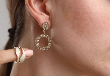 Photo of Woman wearing stylish earring and ring on light background, closeup
