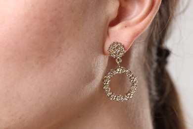 Photo of Woman wearing stylish earring on grey background, macro view
