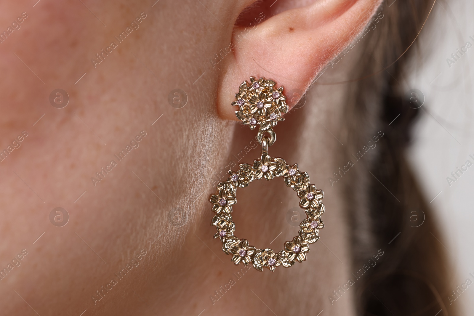 Photo of Woman wearing stylish earring on grey background, macro view