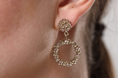 Photo of Woman wearing stylish earring on grey background, macro view