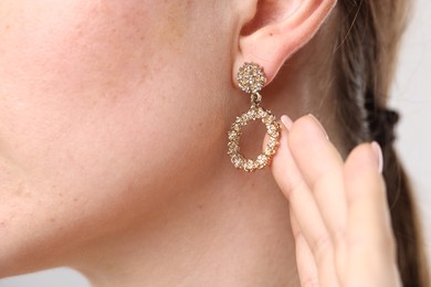 Photo of Woman wearing stylish earring on grey background, macro view