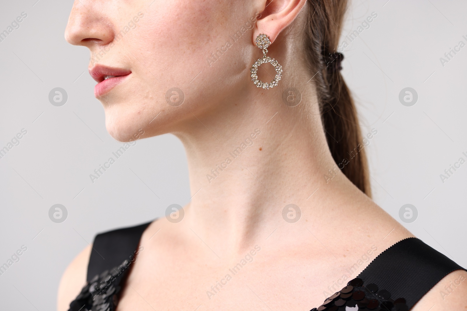 Photo of Woman wearing stylish earring on grey background, closeup