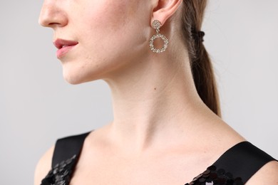 Photo of Woman wearing stylish earring on grey background, closeup