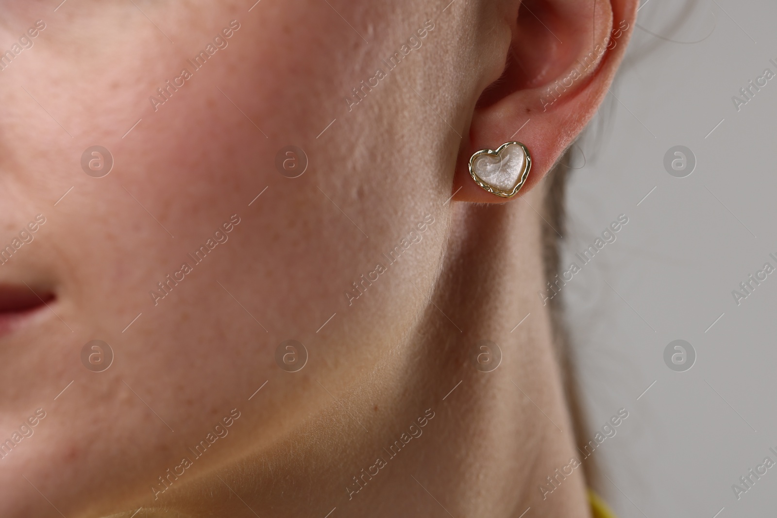 Photo of Woman wearing stylish earring on grey background, closeup