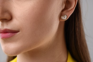 Photo of Woman wearing stylish earring on grey background, closeup