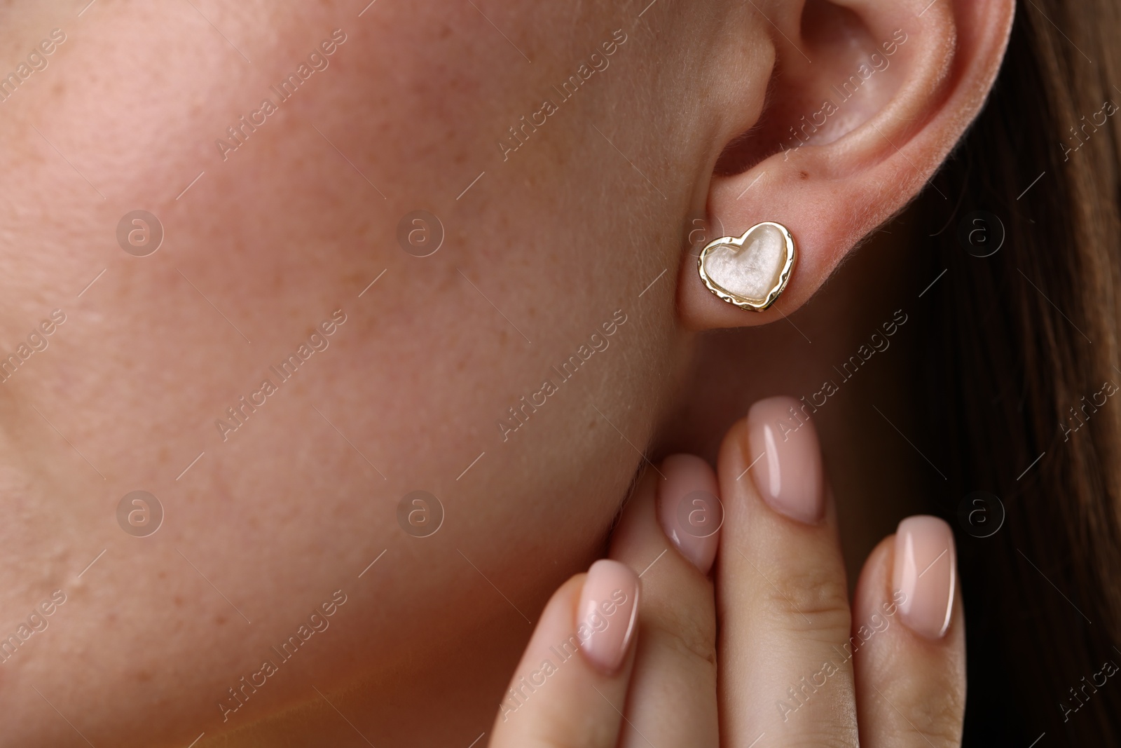 Photo of Woman wearing stylish heart-shaped earring, closeup view