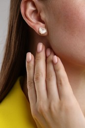 Photo of Woman wearing stylish heart-shaped earring, closeup view
