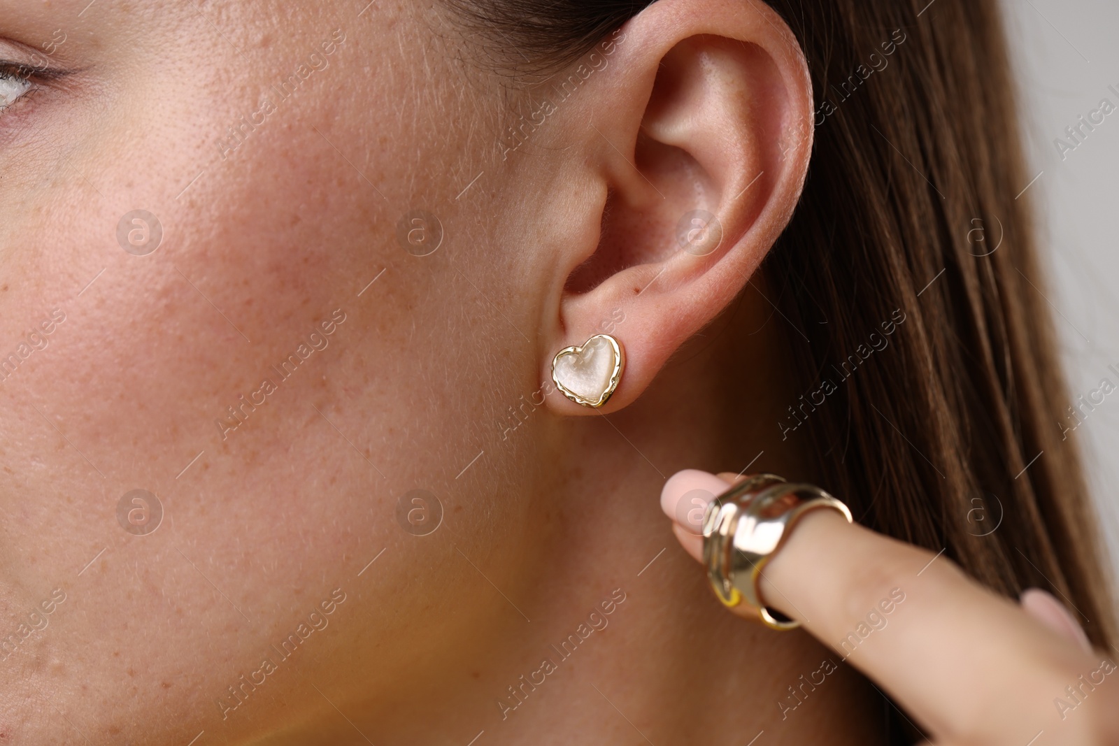 Photo of Woman wearing stylish earring and ring on light background, closeup