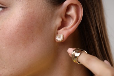 Photo of Woman wearing stylish earring and ring on light background, closeup